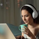 a woman wearing headphones and drinking from a cup